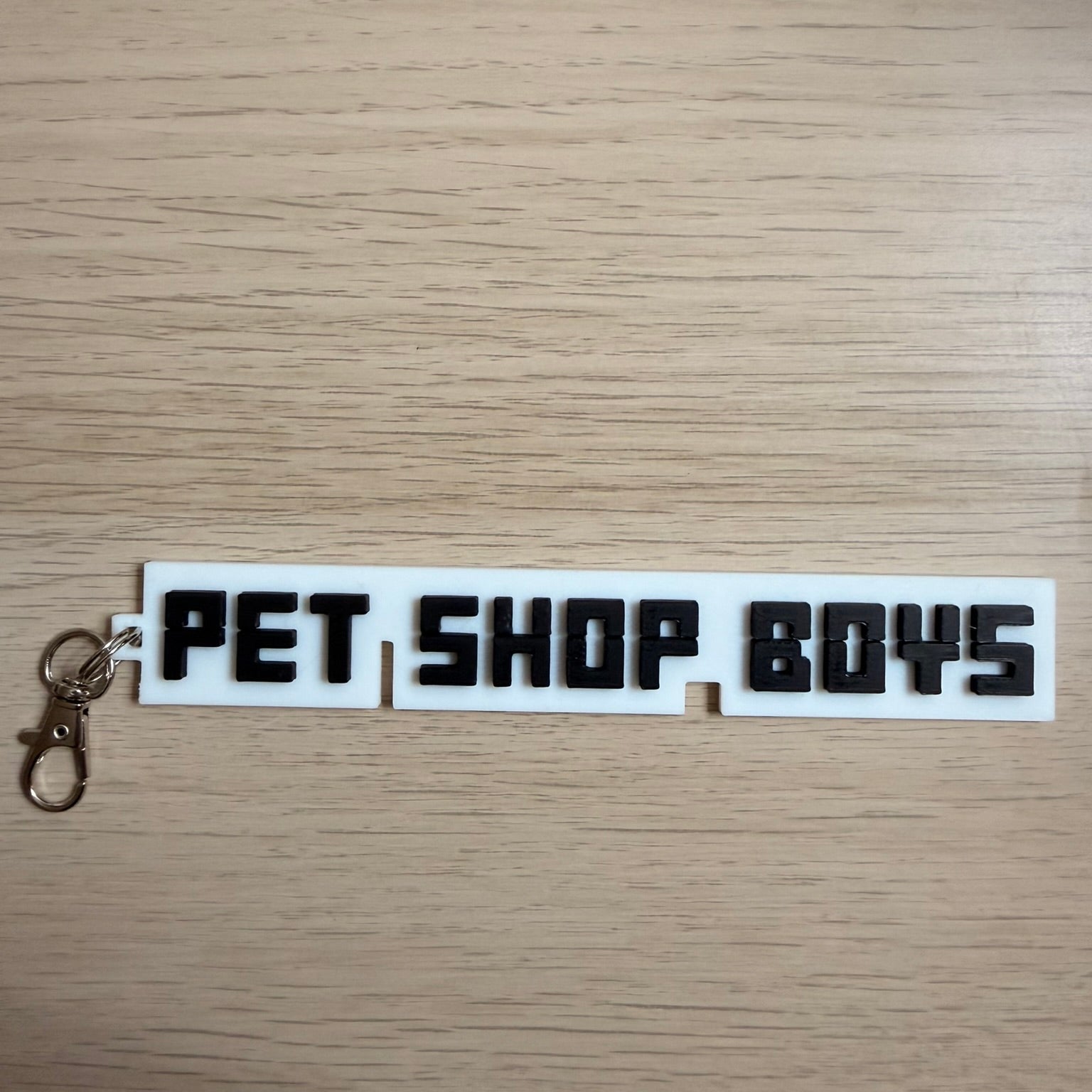 τρισδιάστατο μπρελόκ με το λογότυπο των Pet Shop Boys σε λευκό και μαύρο χρώμα